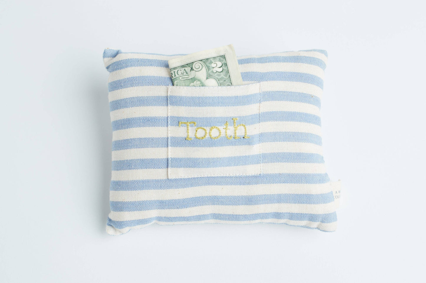 Close-up view showing the striped handwoven cotton fabric and small embroidered pocket of the tooth fairy pillow