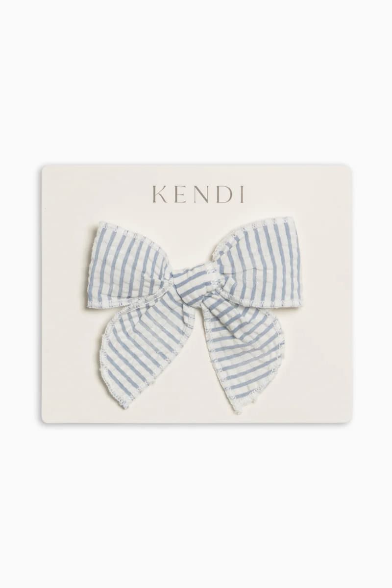 Colored Organics Seersucker hair bow in blue & white shore stripe on Kendi card for flatlay.