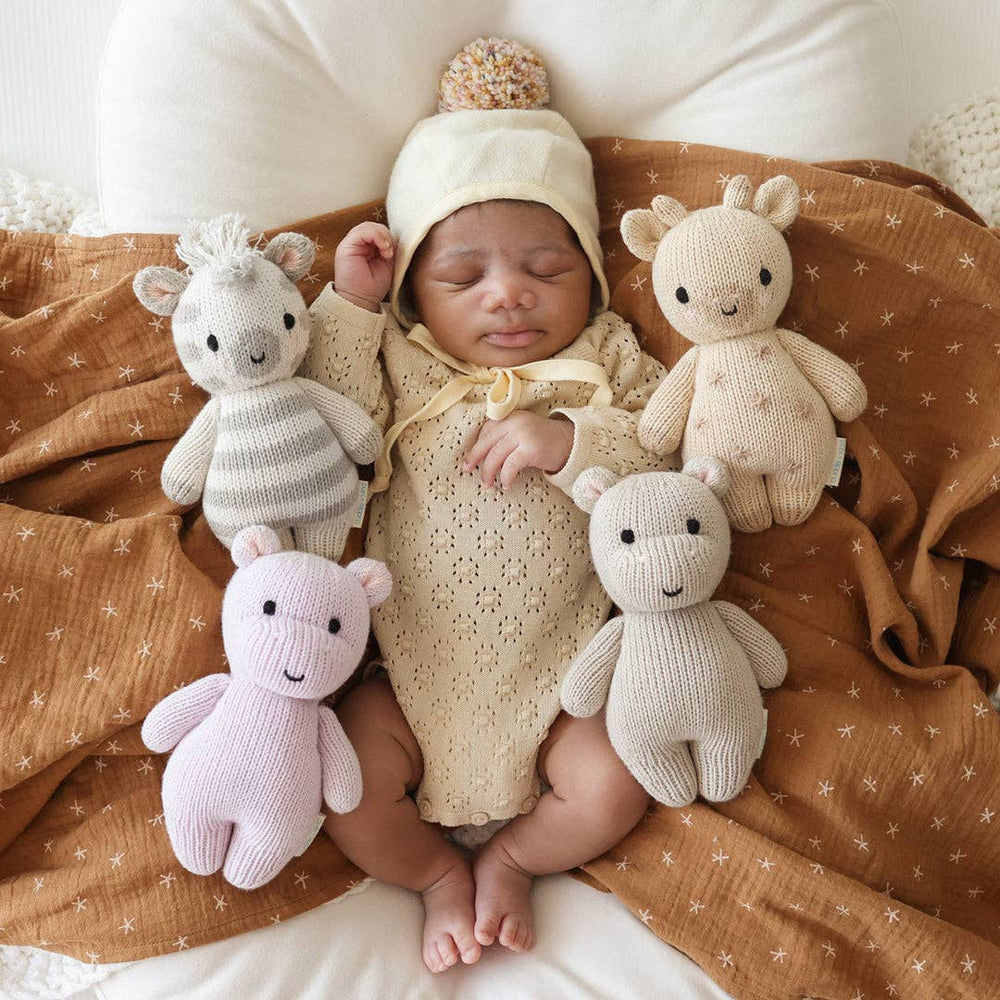
                      
                        Swaddled newborn baby surrounded by Cuddle + Kind zebra and other stuffed animals – safe and sustainable baby gift
                      
                    