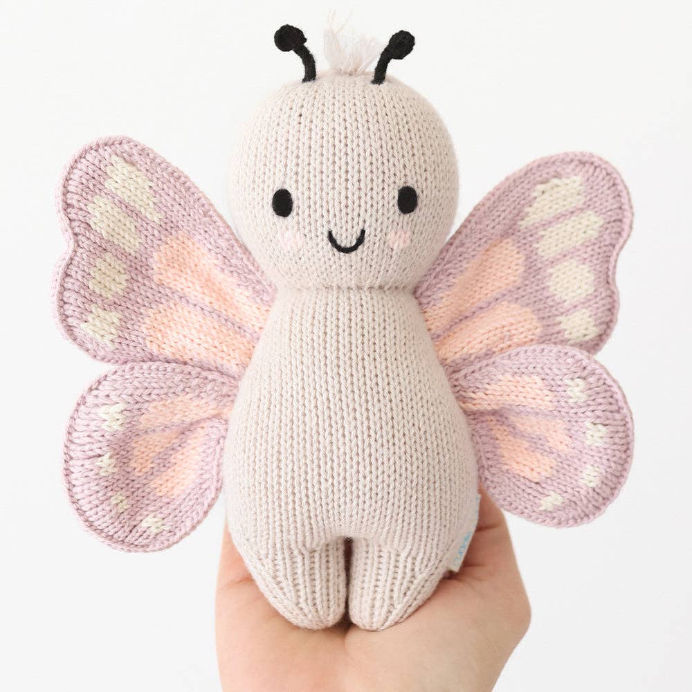 
                      
                        Cuddle + Kind Baby Butterfly held in adult hand for size reference, showing petite 7-inch height and soft texture
                      
                    