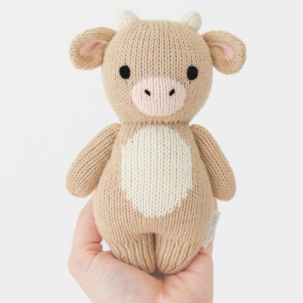 
                      
                        Cuddle + Kind Baby Cow (Jersey) plush doll being held in hand to show 7-inch size, ideal for newborns and toddlers
                      
                    