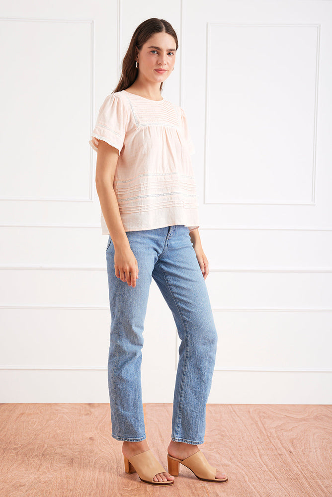 
                      
                        Right side studio view of the Dawn Tee in Bright Bellini, styled with denim to highlight the feminine shape and lace trim.
                      
                    