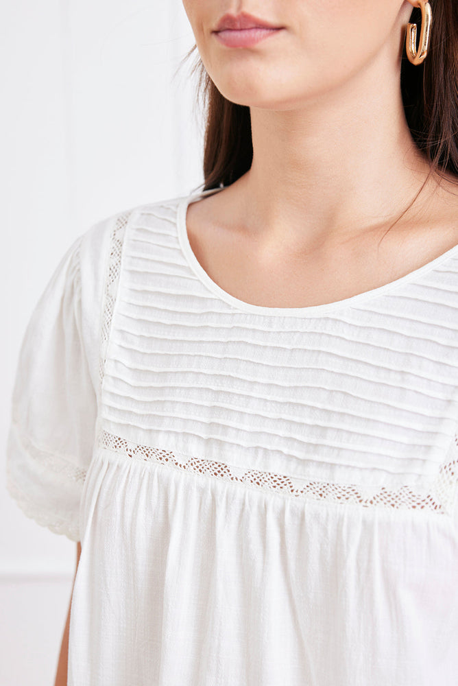 
                      
                        Close-up of the Dawn Tee’s romantic pin tuck stitching and lace paneling at the front neckline.
                      
                    