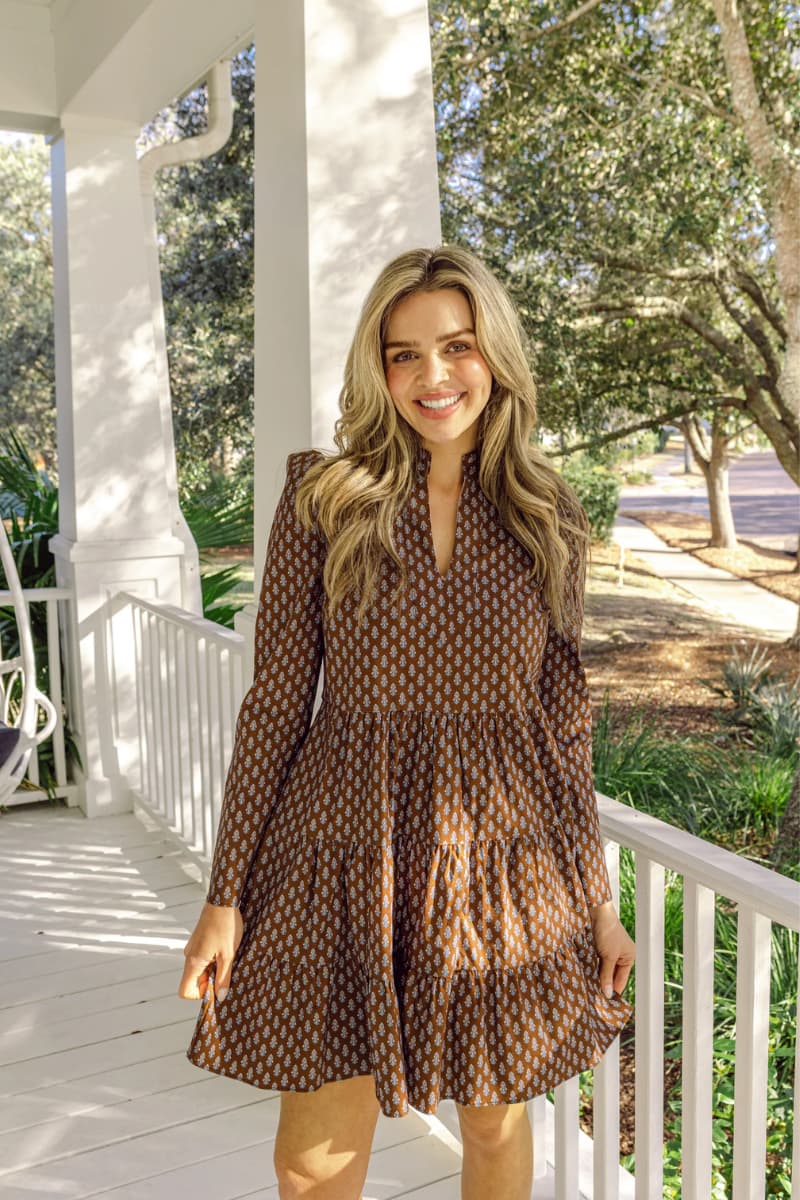 Woman on white porch in Sail to Sable Block Print Tunic Flare Short Dress in beautiful brown for fall.