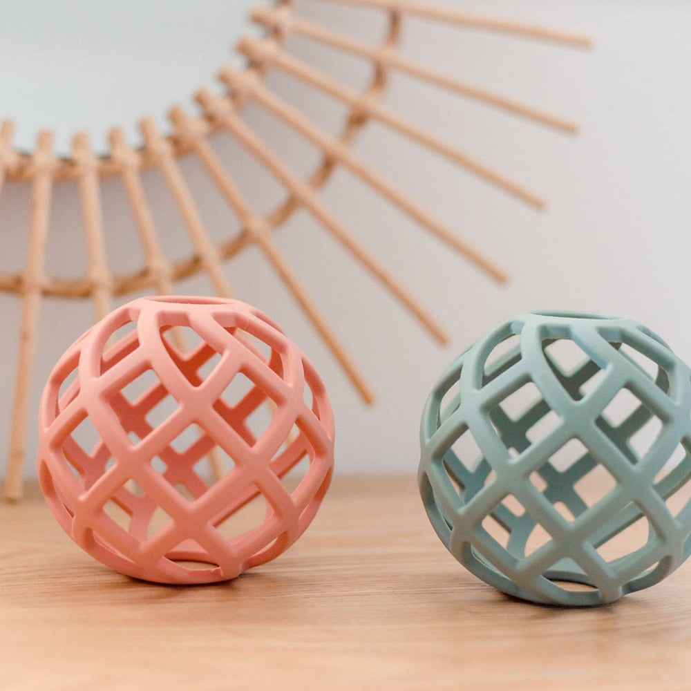 Eco-friendly silicone teether balls in blush pink and ocean blue side-by-side on a white background, safe and sustainable for teething babies