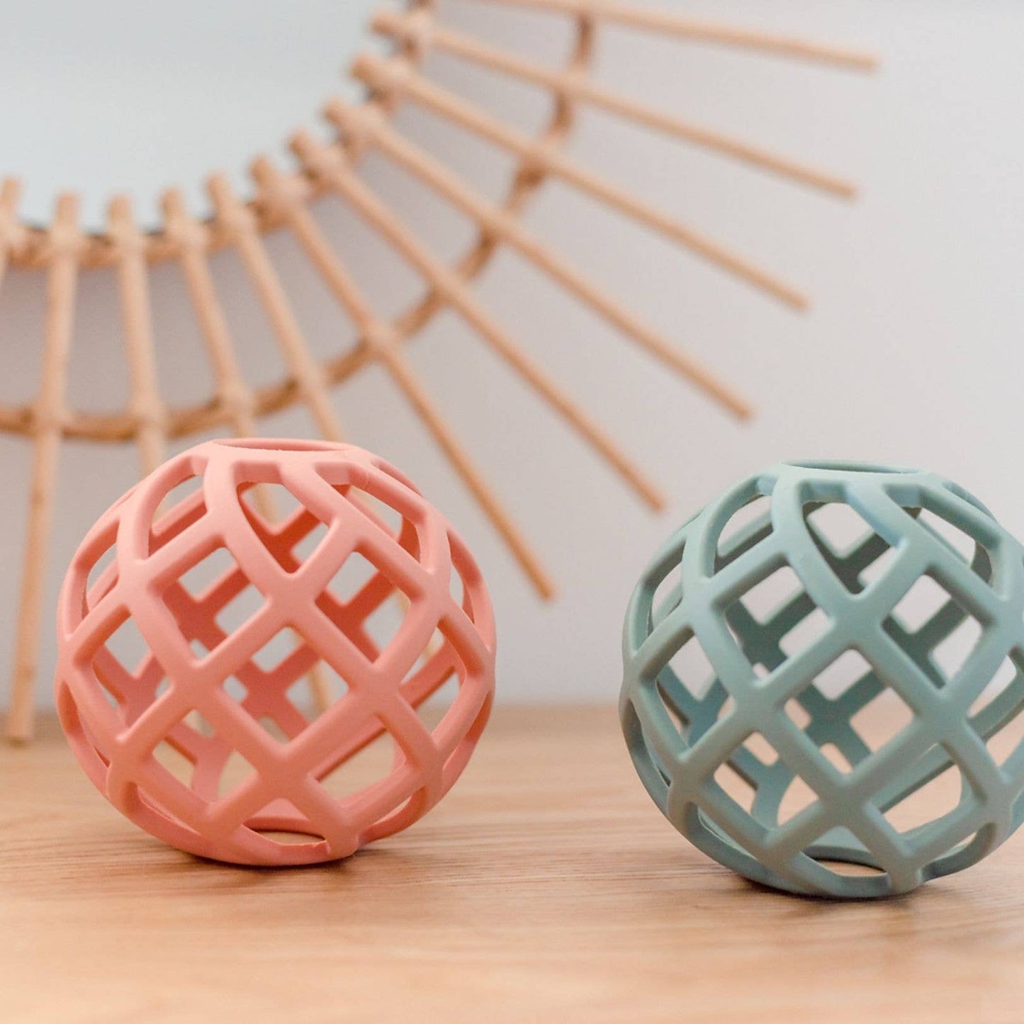 Eco-friendly silicone teether balls in blush pink and ocean blue side-by-side on a white background, safe and sustainable for teething babies