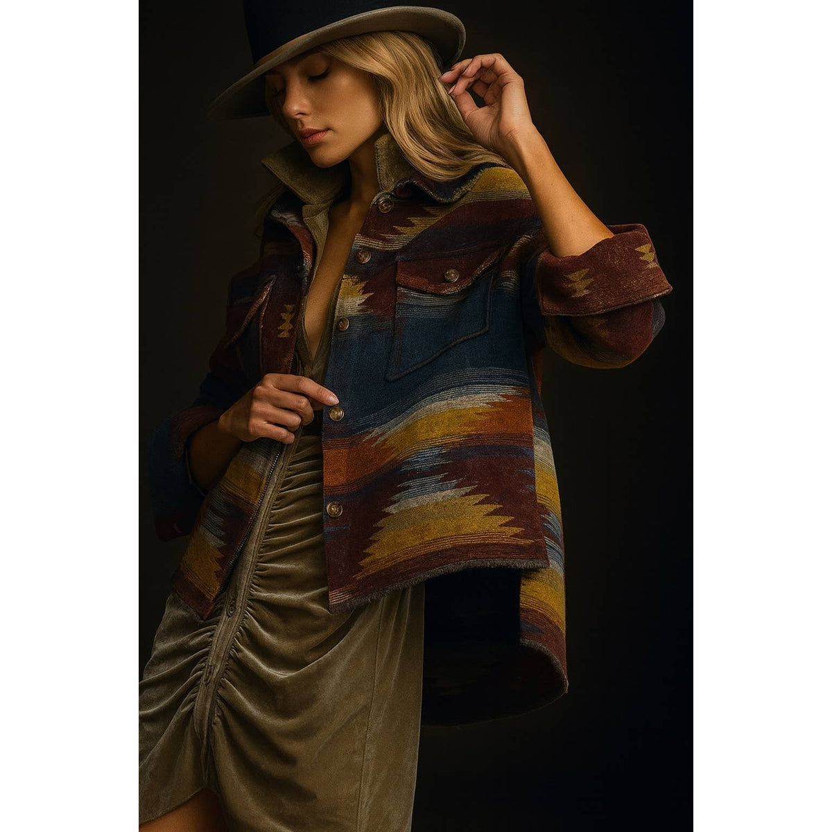 Fall jacket with multicolored southwestern pattern, worn open over a beige ruched dress, styled with a beige wide-brim hat.