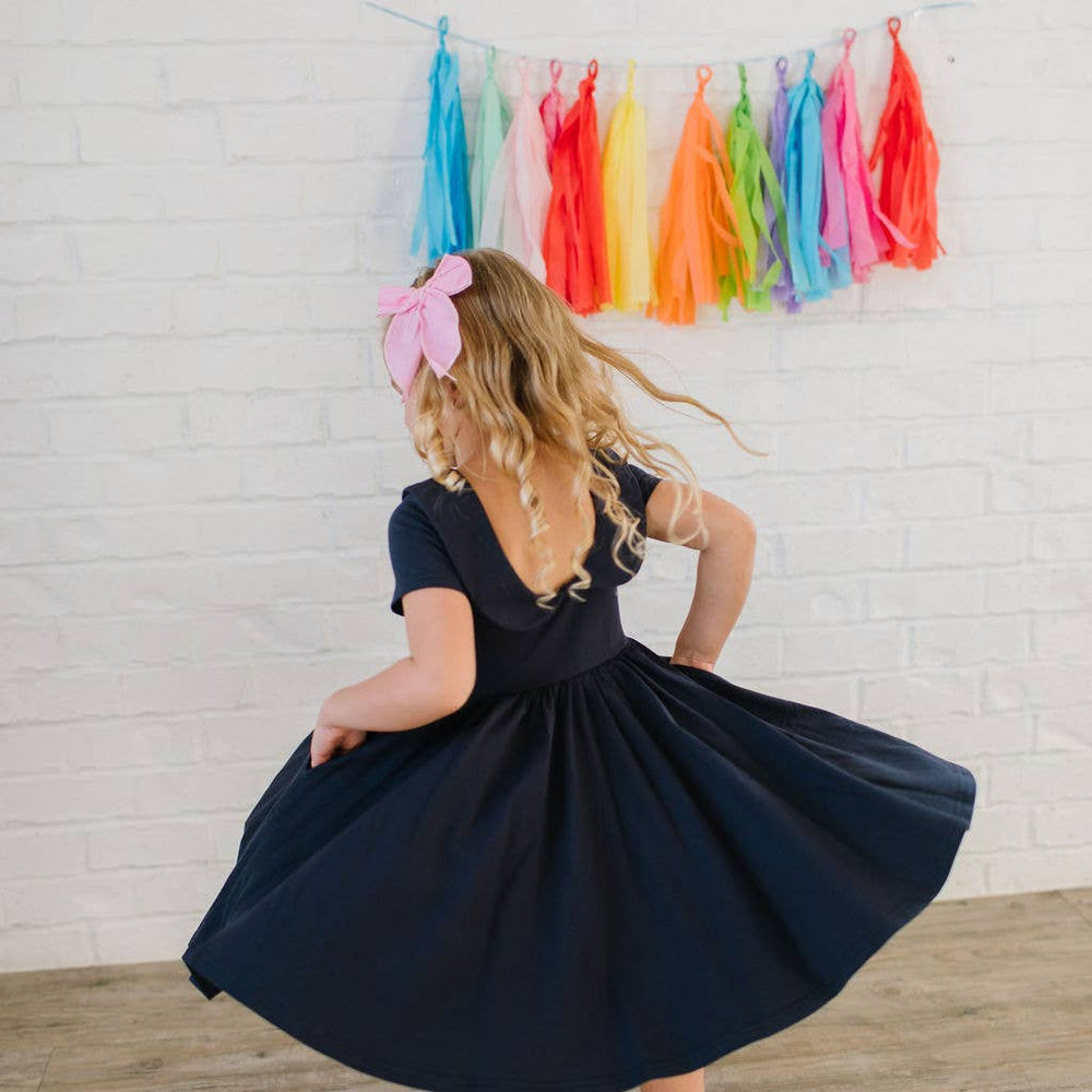 
                      
                        Back view of toddler mid-twirl in the Elizabeth Dress, showing scoop back and flowing skirt.
                      
                    