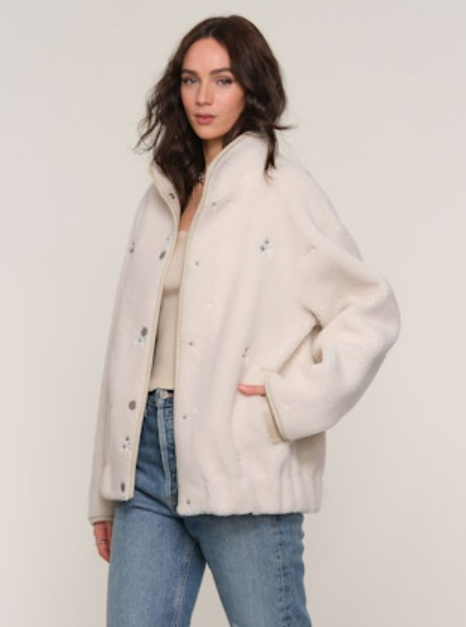 Woman wearing one of our favorite jackets ever with small embroidered flowers. Runs big, size down by 1 or 2 sizes