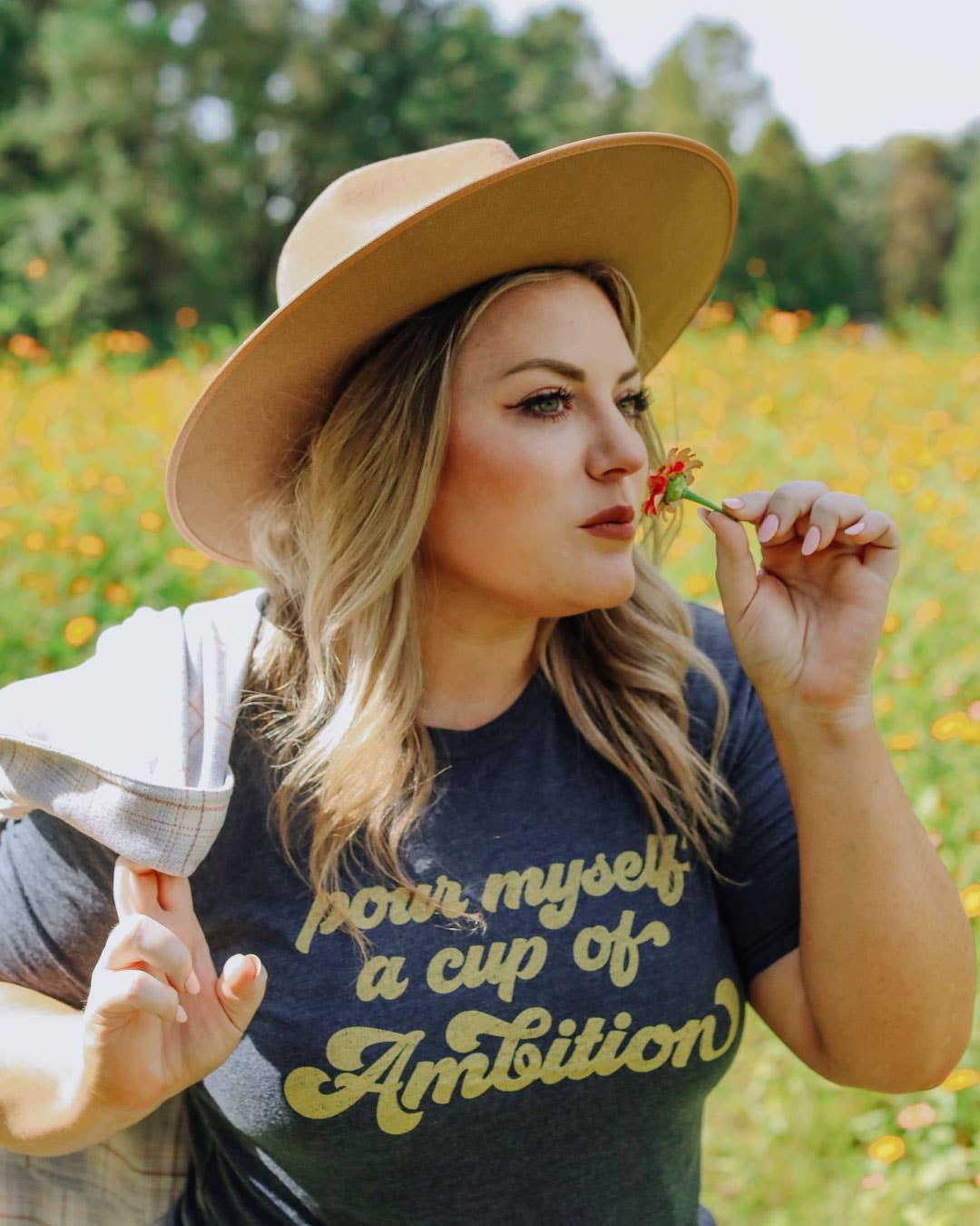 Pour Myself A Cup Of Ambition T-Shirt in navy with yellow text, woman wearing wide-brimmed hat holding a small red flower