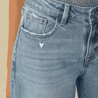Close-up of heart-shaped embroidery detail on Flora barrel jeans.