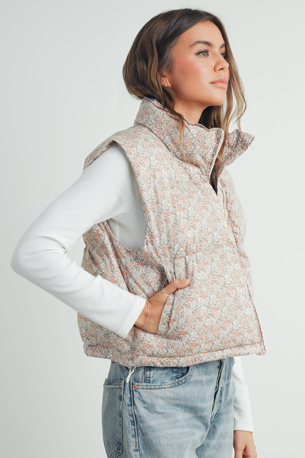 Model wearing the Floral High Neck Puffer Vest with jeans, standing with hands in pockets to show relaxed fit and floral detail