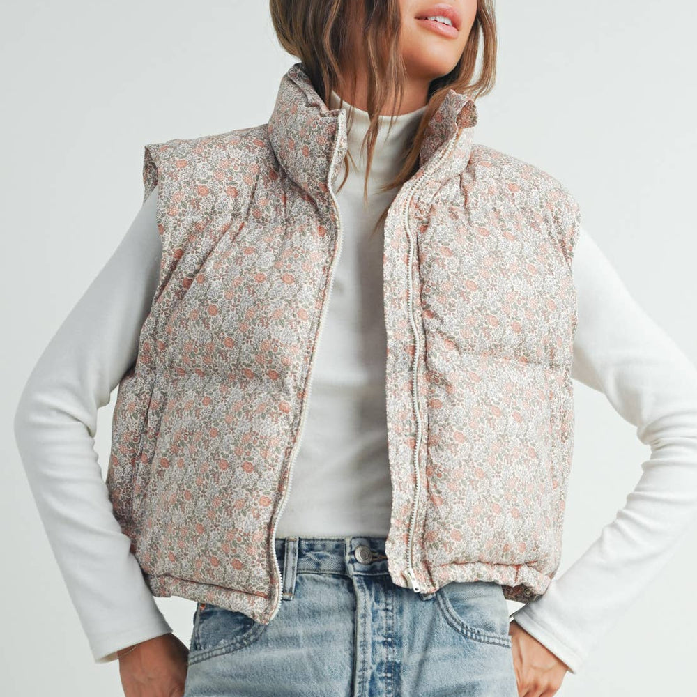 
                      
                        Model smiling over her shoulder while wearing the Floral High Neck Puffer Vest, showing back detail and soft, feminine style
                      
                    