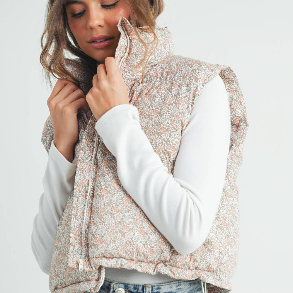 
                      
                        Side view of model wearing the high neck floral puffer vest, showing length and silhouette with casual jeans
                      
                    