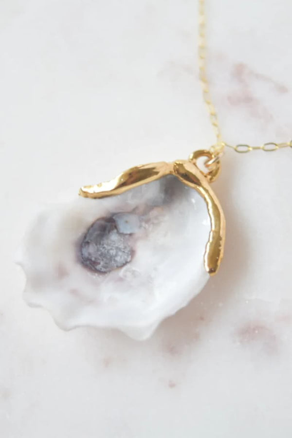 Gold dipped oyster shell necklace from the Sea & Me featuring a white oyster shell with a gold dolphin-shaped pendant and