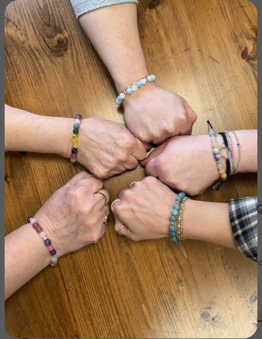 Close-up of women’s hands showcasing handcrafted 8mm gemstone stretch bracelets made during a jewelry workshop at Grace & Haven in Essex, Connecticut.