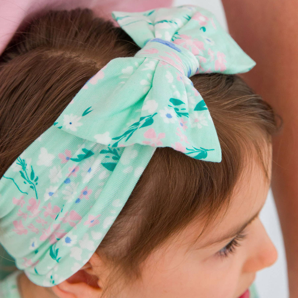 Close-up of big floral bow headband in mint meadow print on girl, showing soft stretchy fabric and bow detail