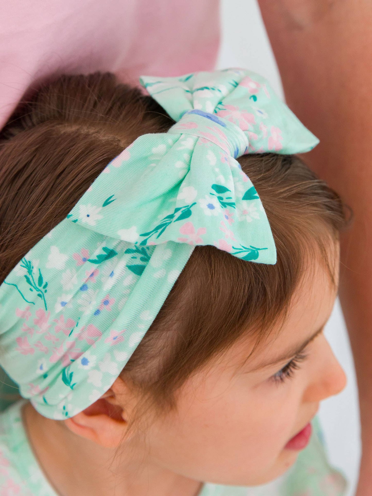 Close-up of big floral bow headband in mint meadow print on girl, showing soft stretchy fabric and bow detail