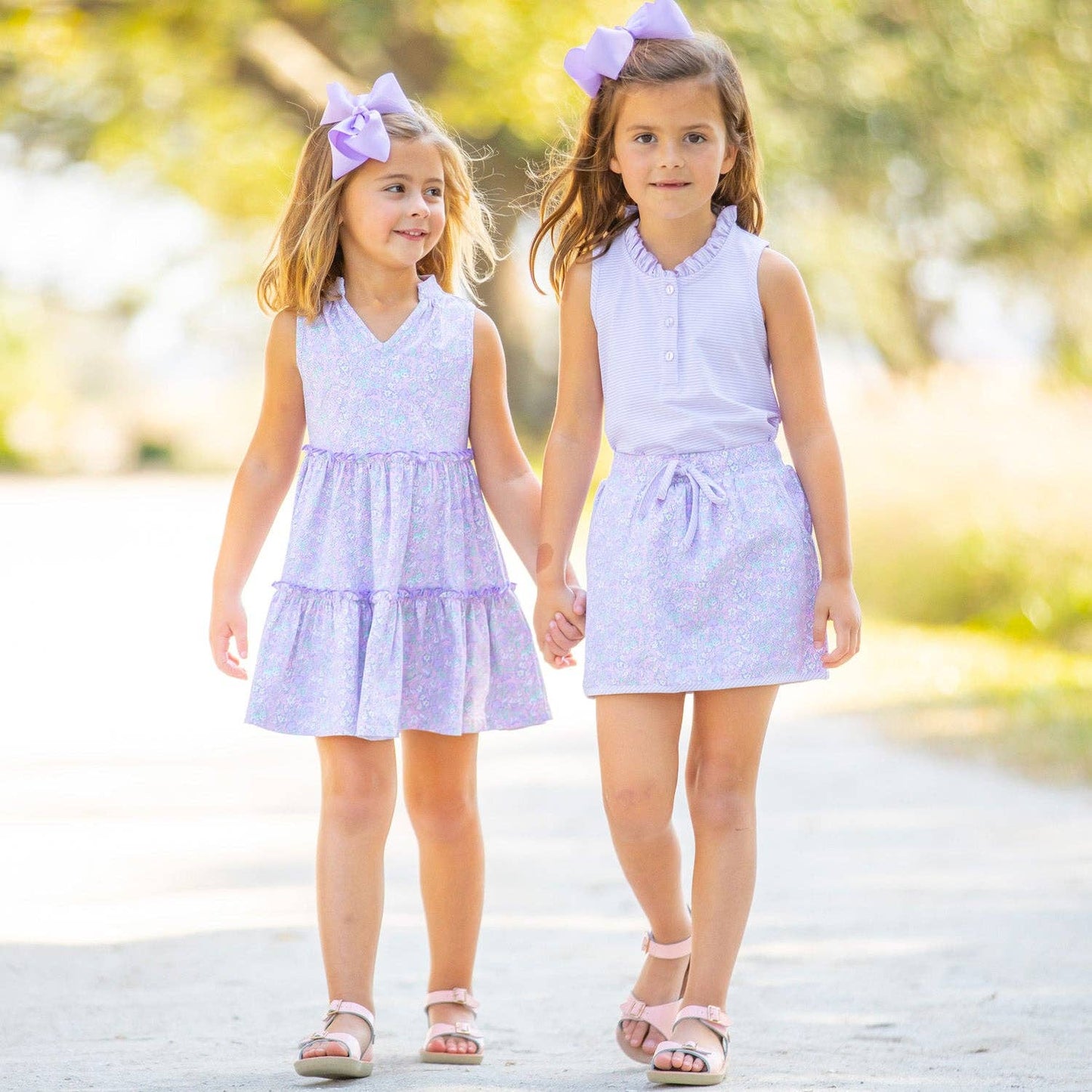 Front view of a girl wearing the St. Simons Stripe Ruffle Neck Polo paired with a skirt, perfect for school days, family outings, or spring adventures.
