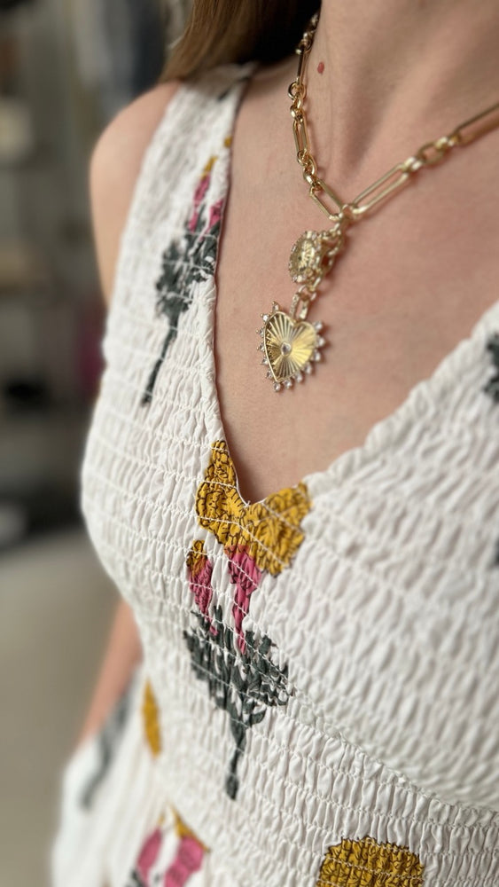 
                      
                        Close-up of the Gold Heart Charm Necklace by Stillwaters USA styled with the Marea Cora Dress, showcasing radiant gold tones and feminine details for a refined look
                      
                    