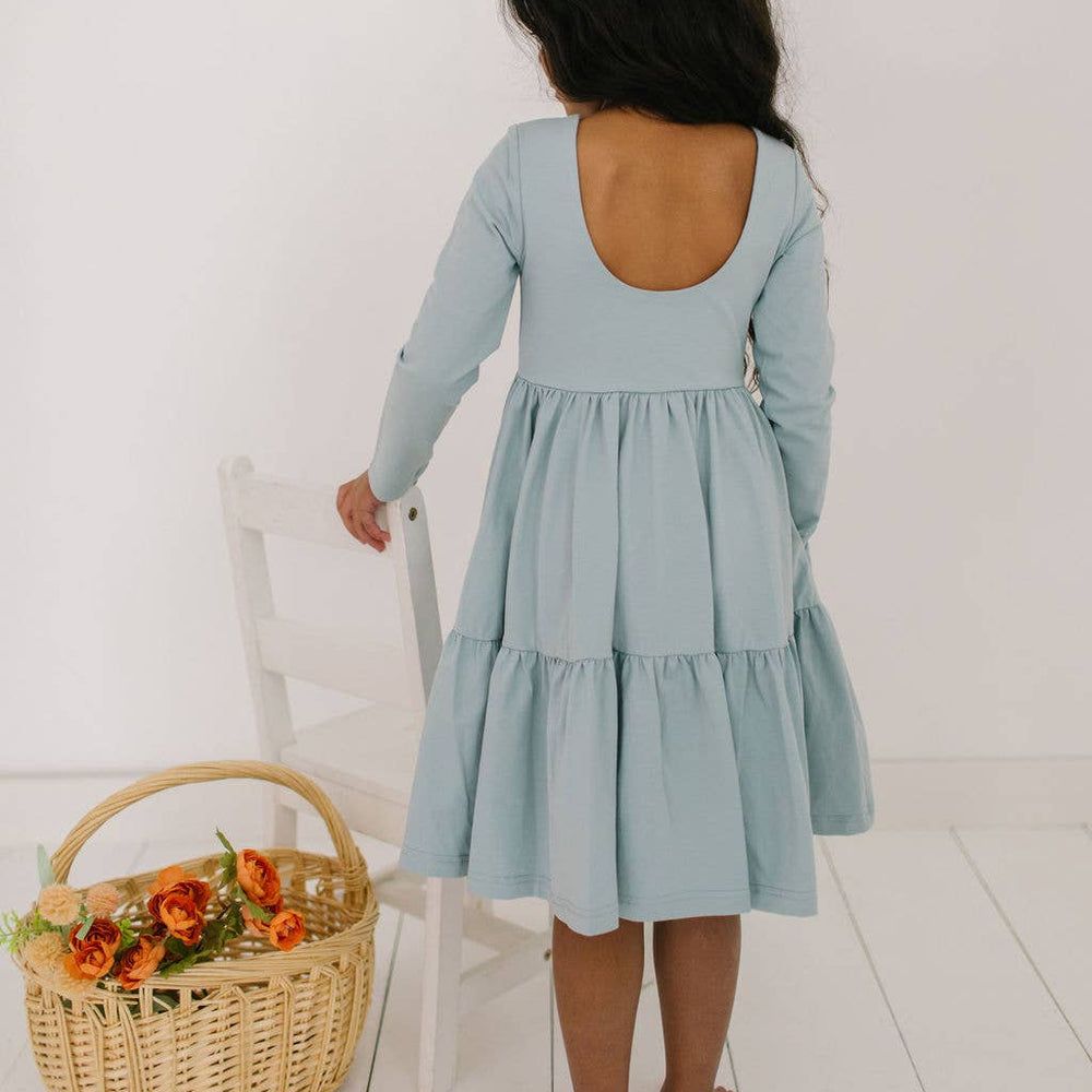 Back view of the Gwendolyn Ruffle Dress in dusty blue on a toddler model, featuring the scoop back and ruffle detailing.