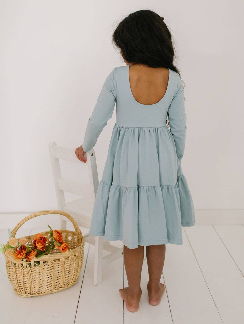 Back view of the Gwendolyn Ruffle Dress in dusty blue on a toddler model, featuring the scoop back and ruffle detailing.
