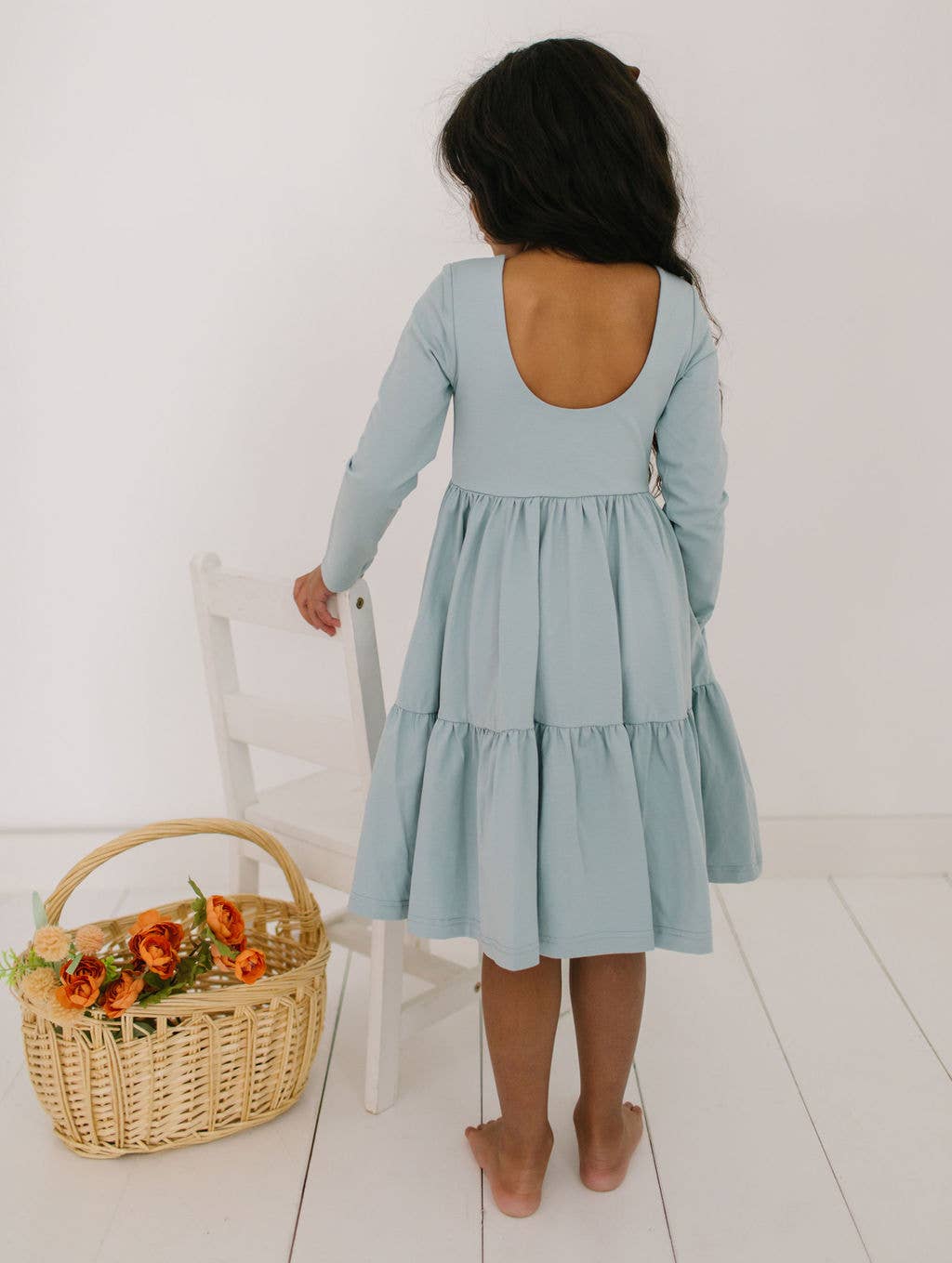 Back view of the Gwendolyn Ruffle Dress in dusty blue on a toddler model, featuring the scoop back and ruffle detailing.