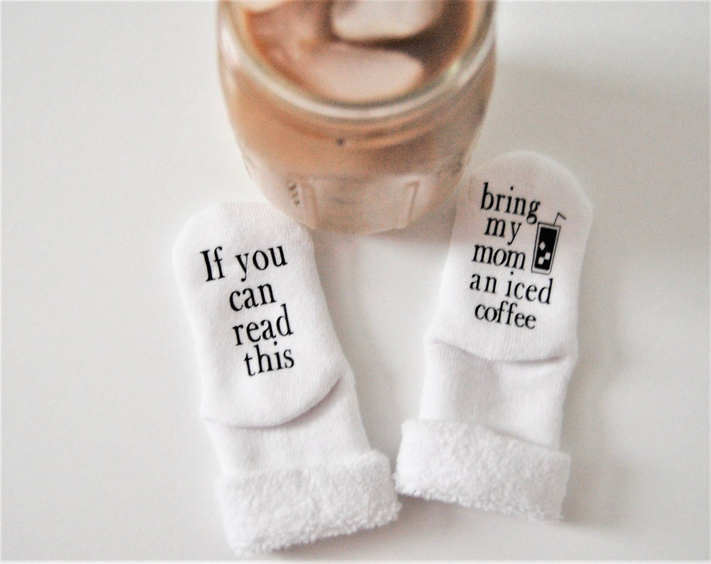 Close-up of baby socks with “Bring My Mom an Iced Coffee” message in bold text.