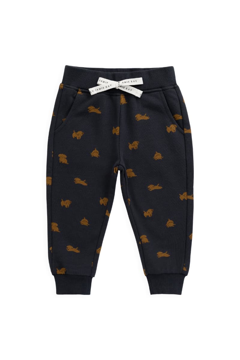 A pair of toddler jogger pants in dark navy blue with an all-over brown puppy dog print, featuring a white bow with a brand label at the waistband that reads "Jamie Kay". Availalbe with matching organic sweatshirt at graceandhaven.co with free shipping