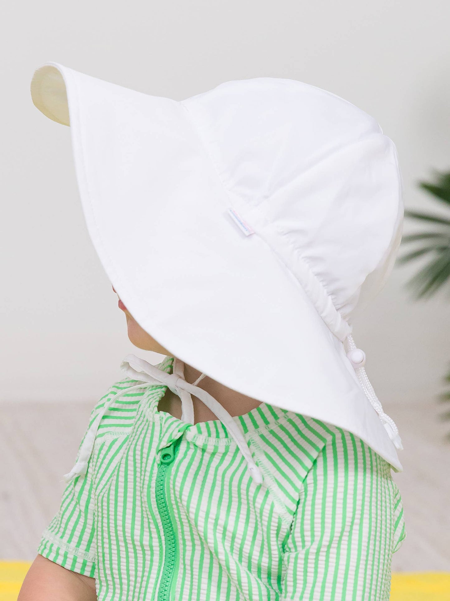 Close-up side view of kids white UPF 50+ sun hat on child, showing lightweight fabric and chin tie