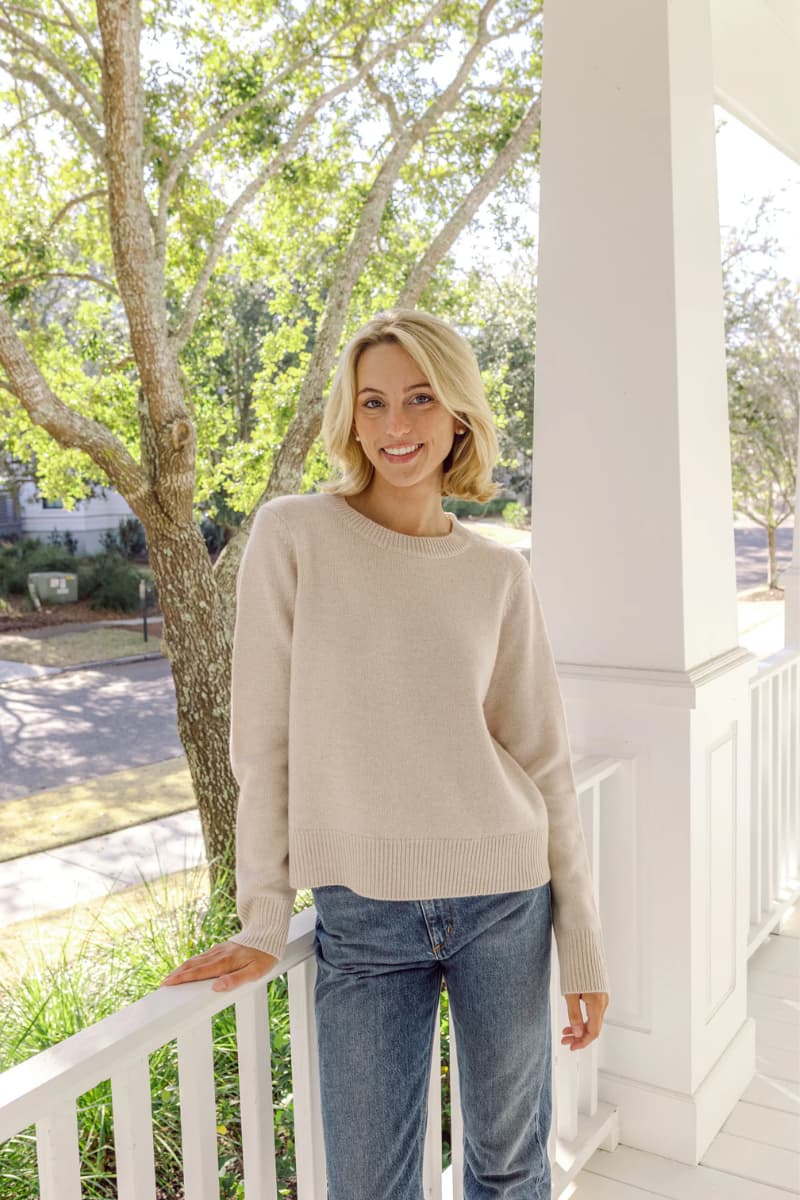 Woman smiling in a beige crew neck wool & cashmere blend sweater by Sail to Sable paired with basic denim for the perfect fall outfit. 