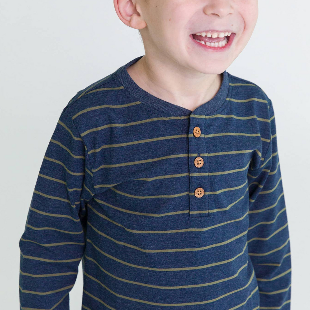 
                      
                        Young boy wearing the Boys Dusty Olive Stripe Knit Long Sleeve Henley Tee, smiling in a studio setting.
                      
                    