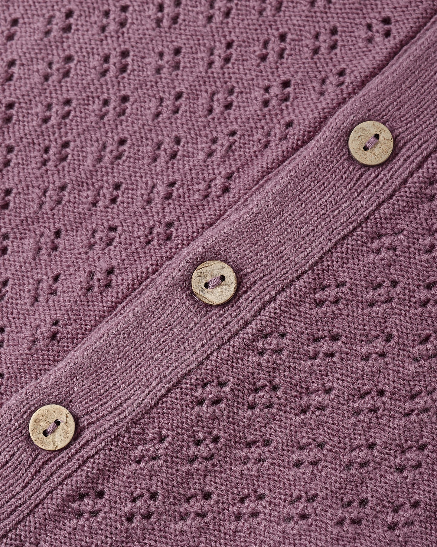 Close-up of coconut button closure and knit texture on the Mulberry Long Sleeve Bubble Romper by Quincy Mae.