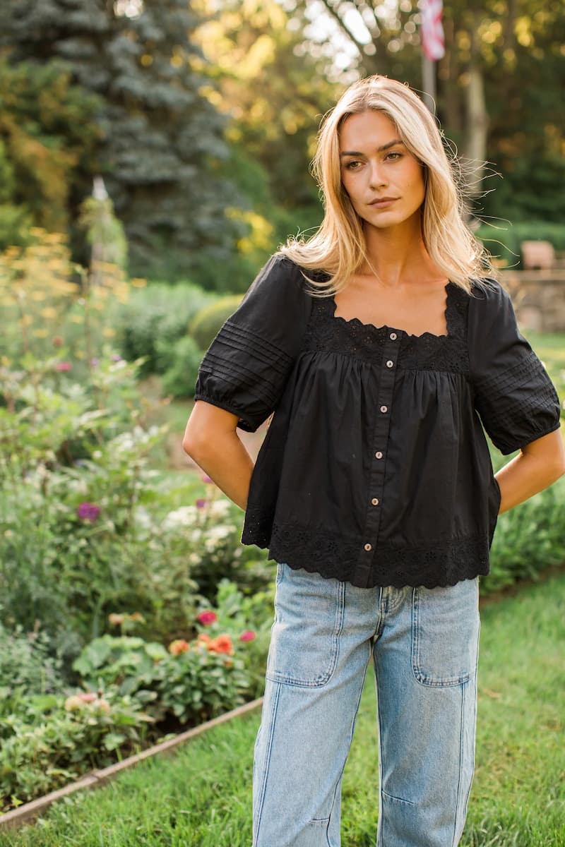 Marea Liza black cotton eyelet top with puff sleeves, styled with blue jeans outdoors.