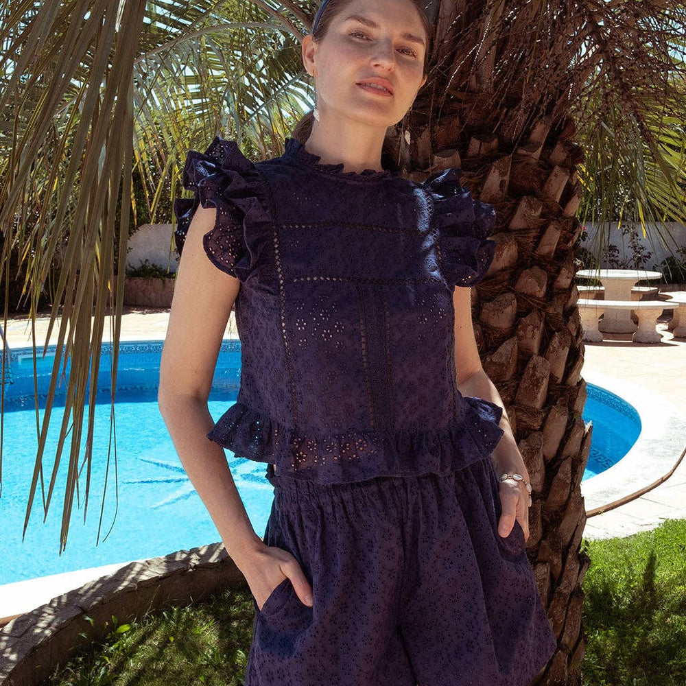 
                      
                        Model wearing navy Olivia shorts and Sasha top in front of a palm tree, styled for a relaxed vacation outfit.
                      
                    
