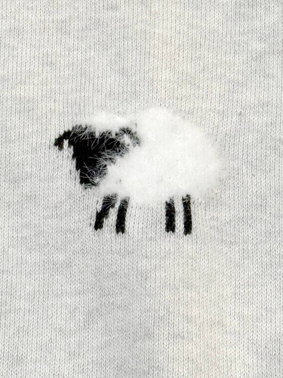 Close-up of sheep jacquard knit pattern with embroidery and appliqué on Viverano organic cotton baby jumpsuit