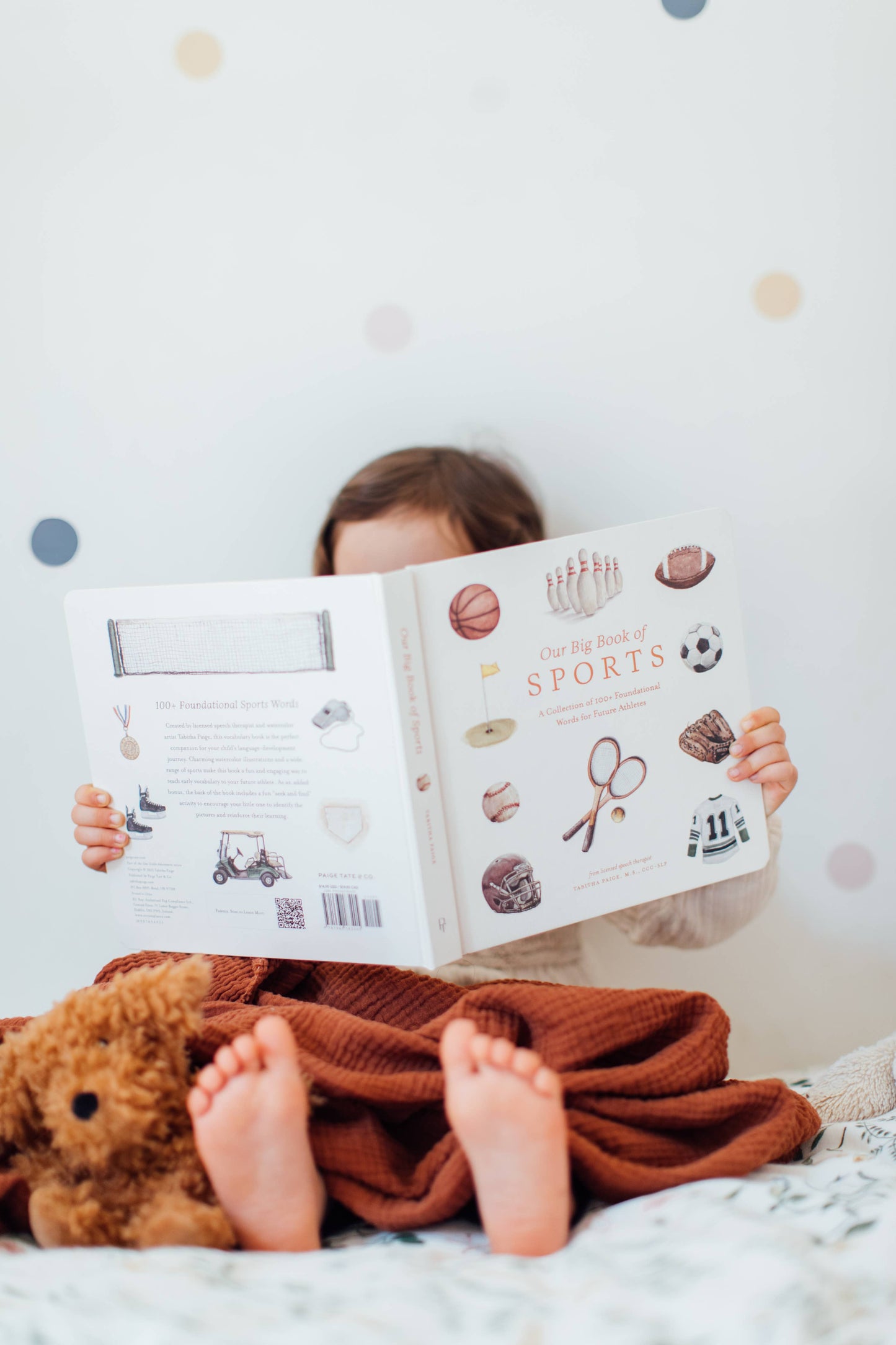 Toddler exploring Our Big Book of Sports board book at home, interacting with pages