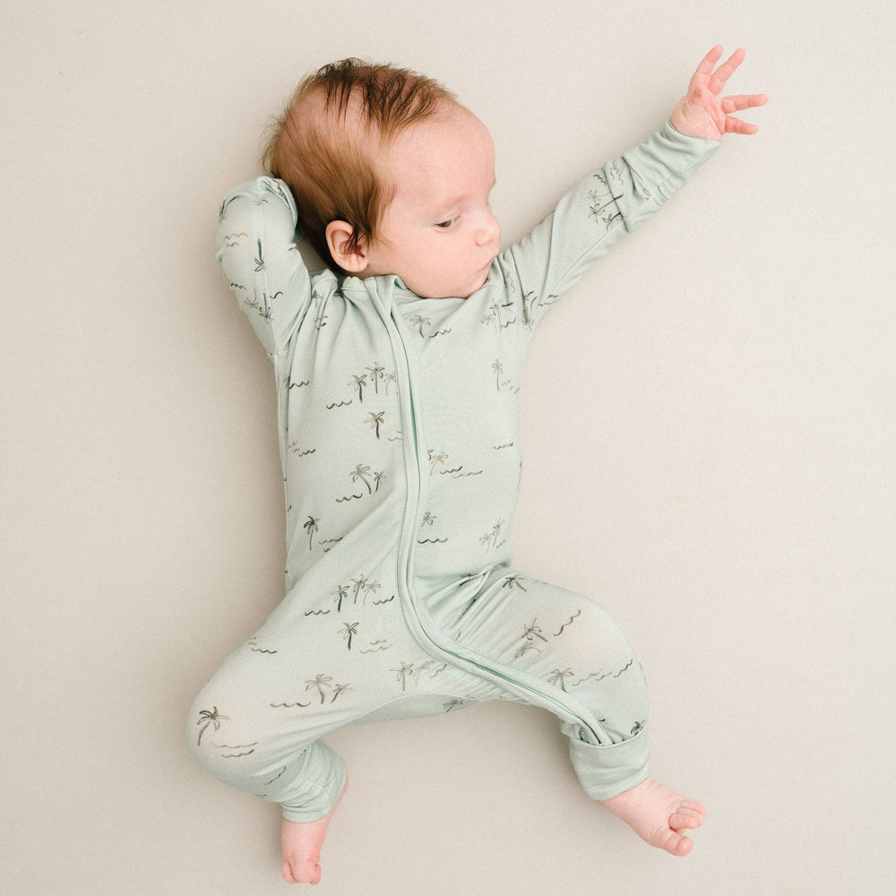 
                      
                        Baby laying on back in crib wearing Palm Breeze Bamboo Sleeper, arms stretched out comfortably.
                      
                    