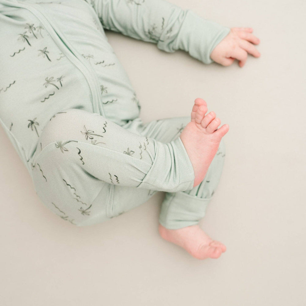 
                      
                        Baby in Palm Breeze Bamboo Sleeper with fold-over mittens covering hands for warmth and protection.
                      
                    