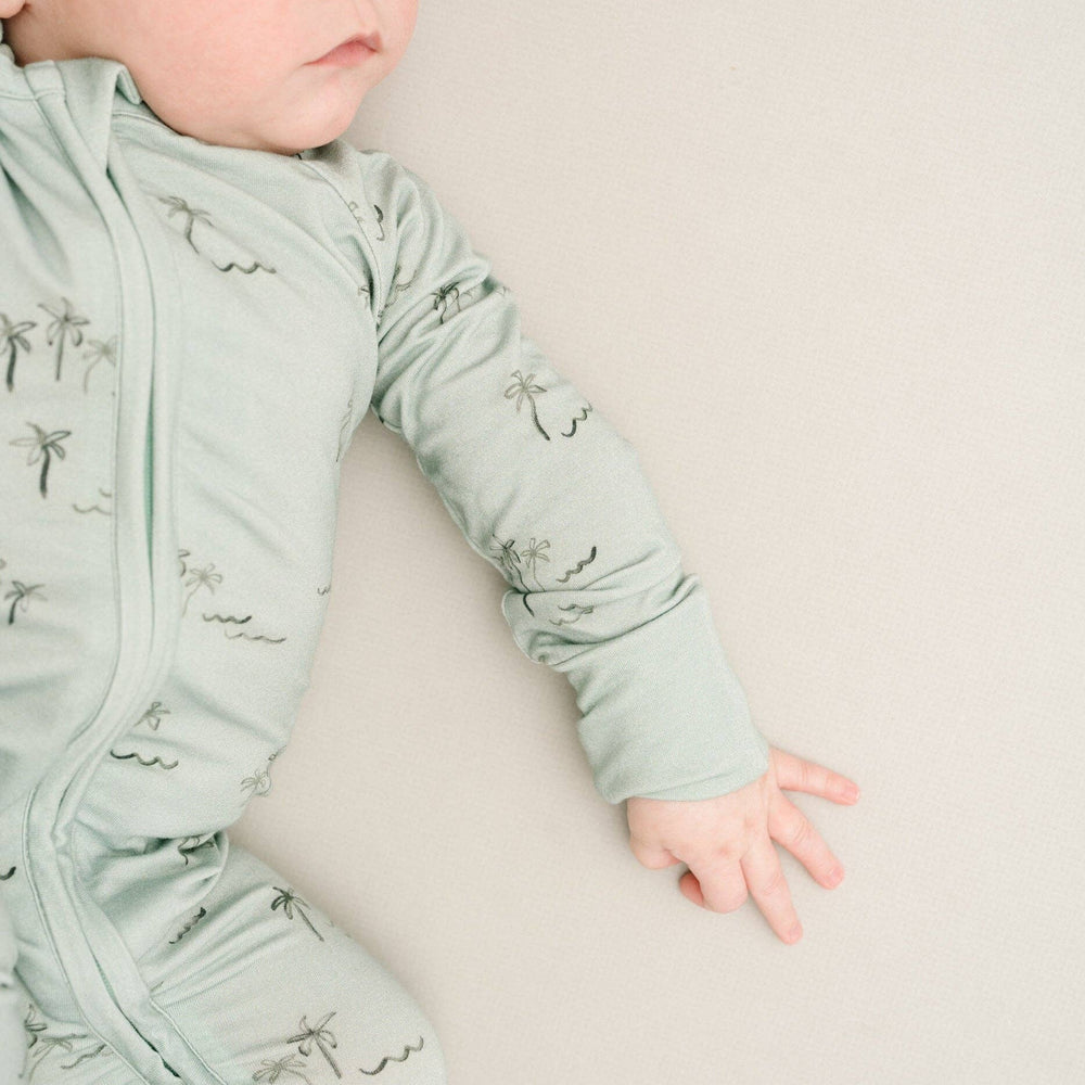
                      
                        Baby lying on side in Palm Breeze Bamboo Sleeper, showing soft stretch and snug fit.
                      
                    