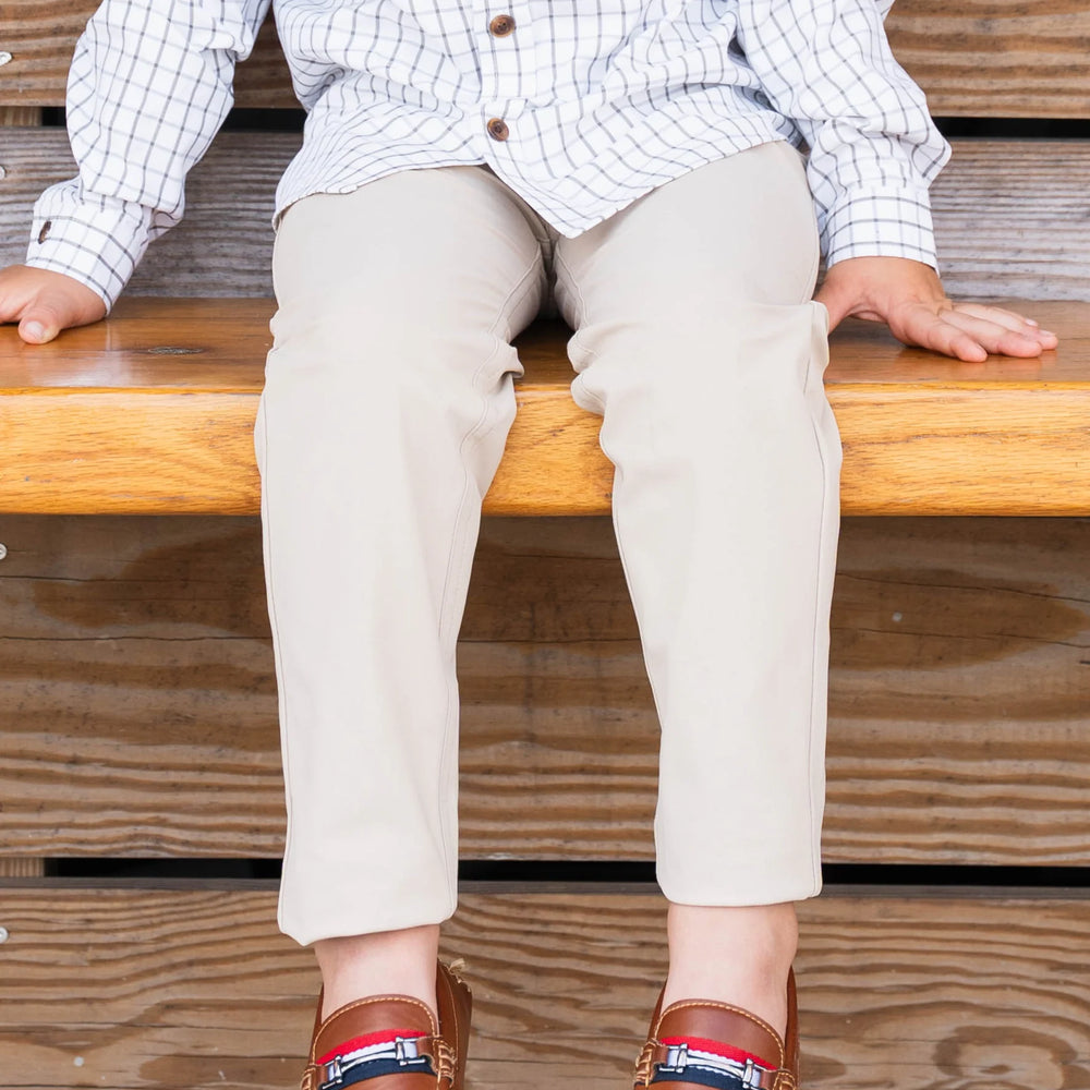 Young boy sitting wearing Par Performance Pants with loafers, highlighting versatile style and comfortable fit for kids.