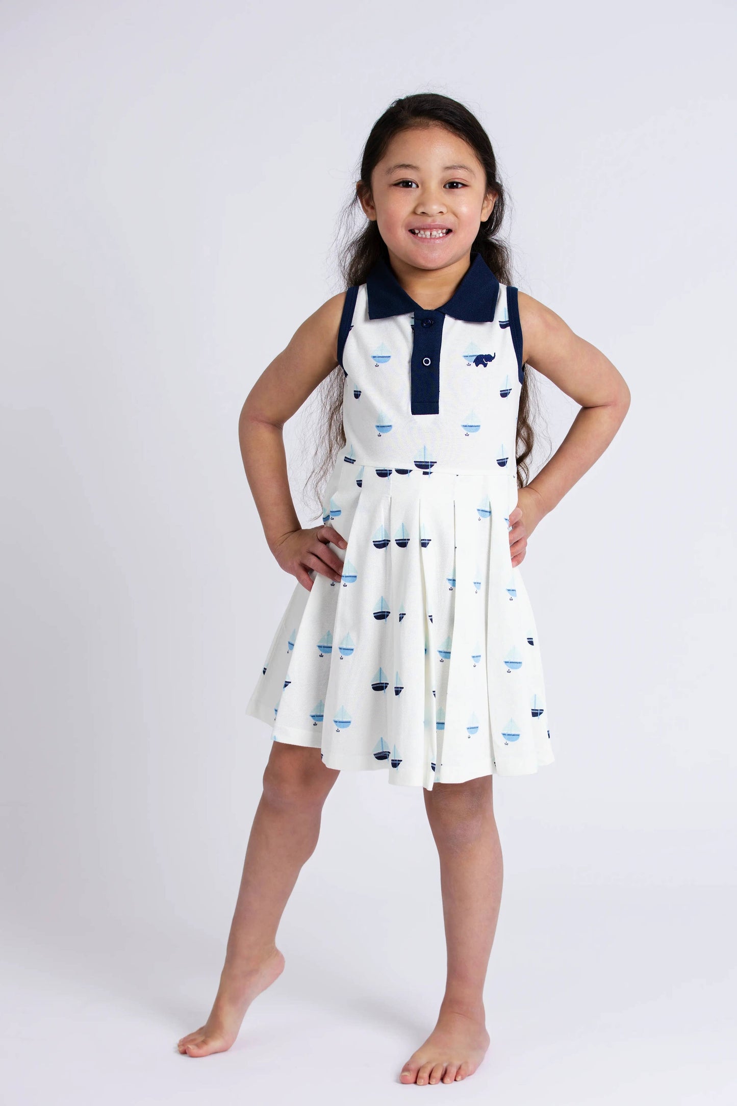 Girl wearing Anchor Down pleated tennis dress with hands on hips, showing classic silhouette and collar