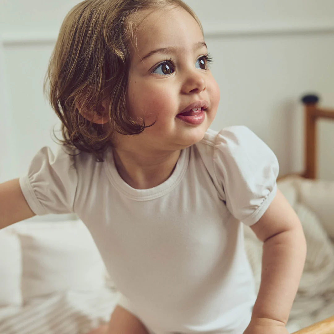 Baby wearing puff sleeve onesie in soft pink, showing a sweet and feminine look for everyday wear