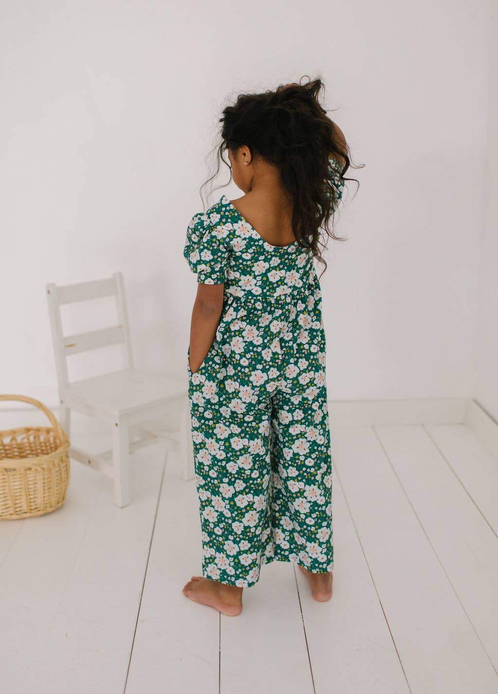 Back view of toddler model wearing the puff sleeve romper, highlighting the relaxed fit and cropped wide-leg design.