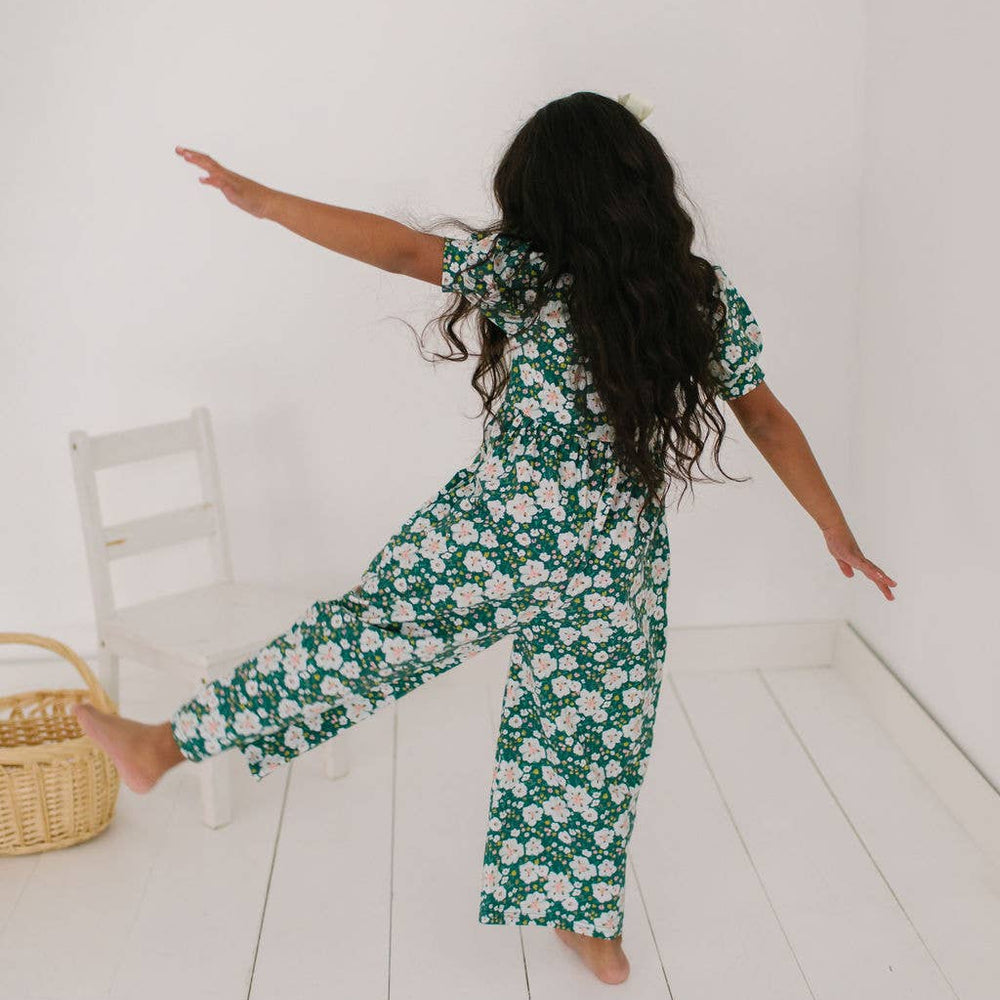 
                      
                        Toddler model with leg out in the puff sleeve romper to show the fullness and soft drape of the cotton blend and wide leg from the back.
                      
                    