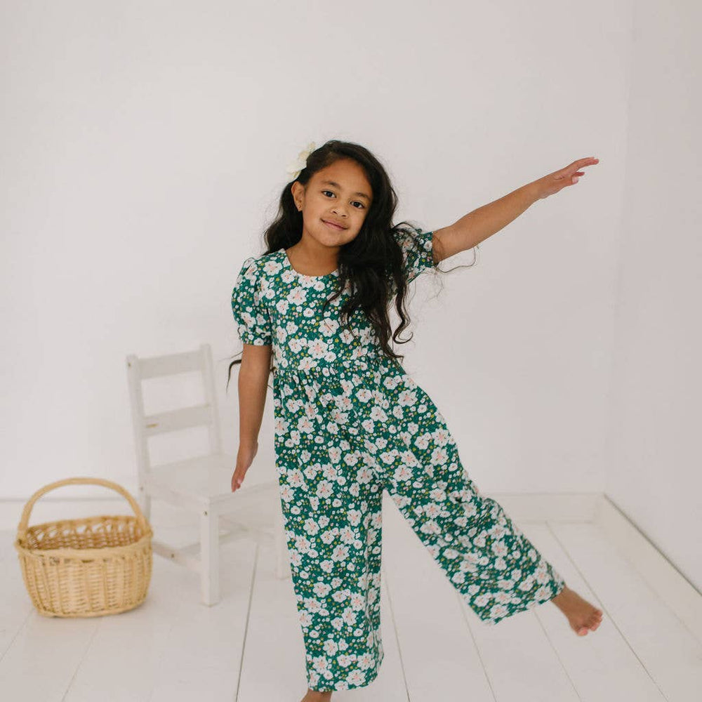 
                      
                        Toddler model with leg out in the puff sleeve romper to show the fullness and soft drape of the cotton blend and wide leg.
                      
                    