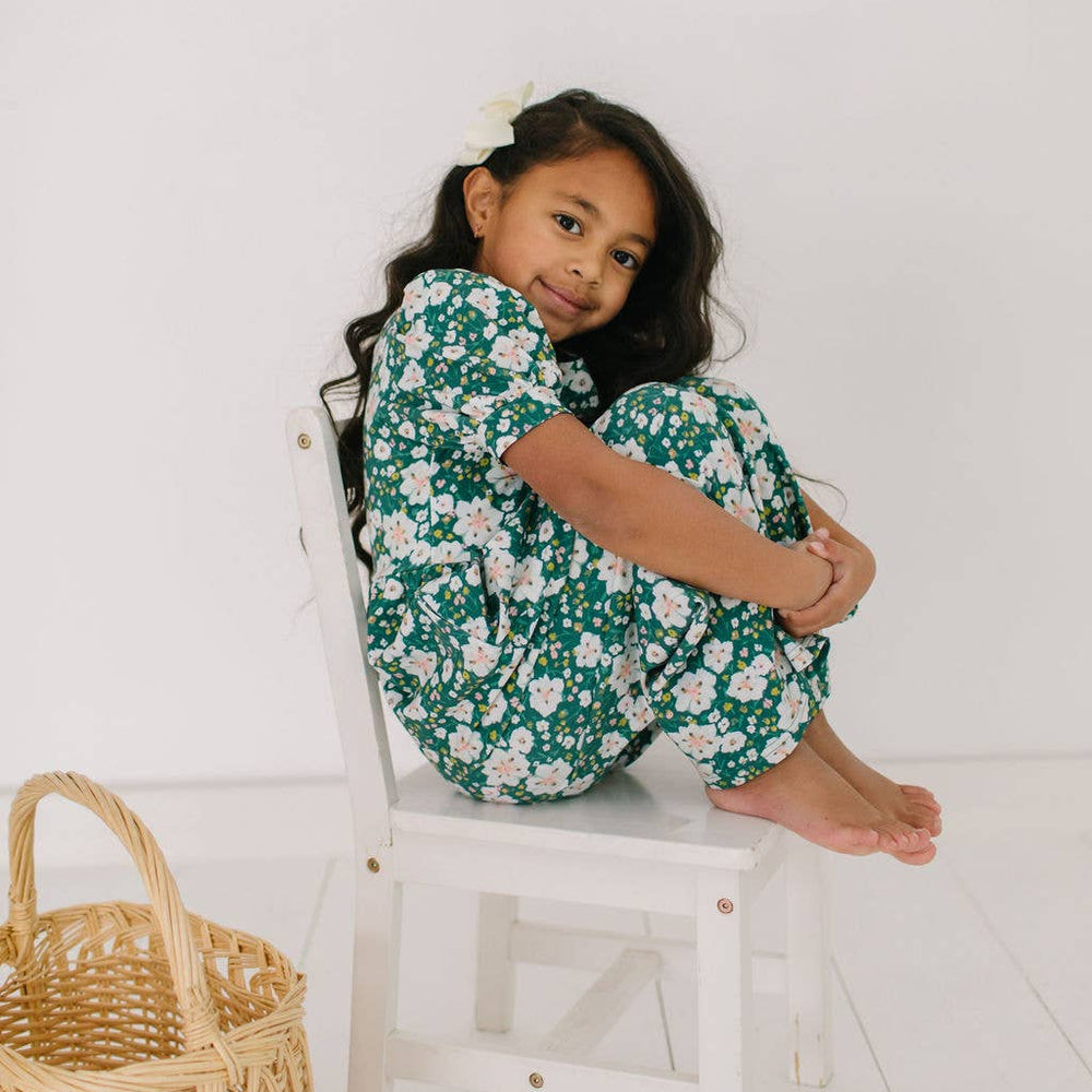 Toddler model sitting in the puff sleeve romper, showing the puffy sleeves and comfortable fit.