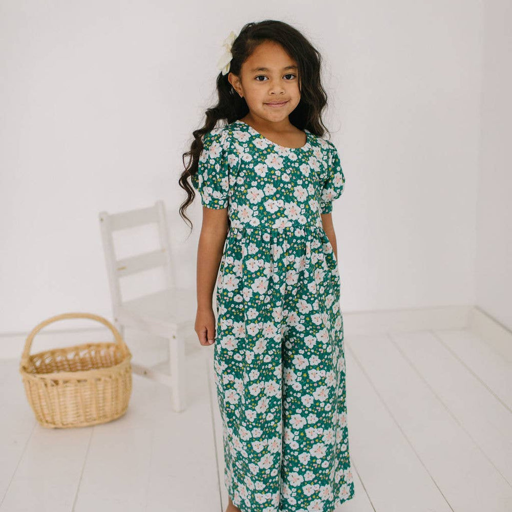 
                      
                        Toddler model standing in the puff sleeve romper, highlighting the playful wide-leg crop and quality of the soft fabric.
                      
                    