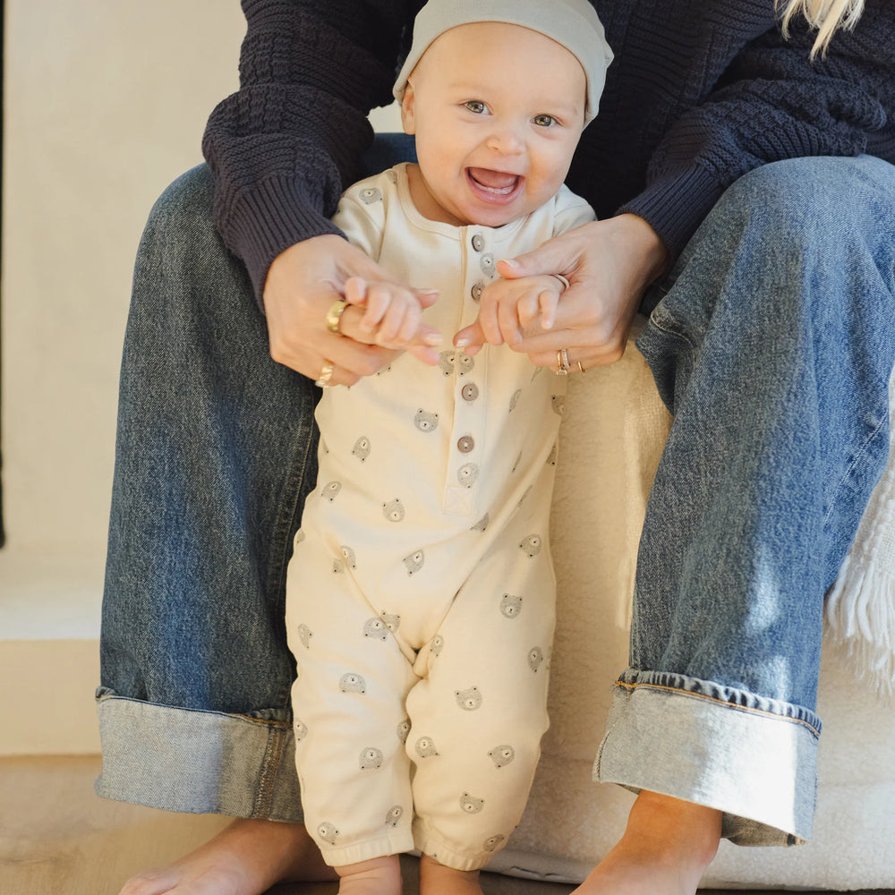 
                      
                        Smiling baby standing with mom’s help in Quincy Mae long sleeve bears jumpsuit, organic cotton one-piece.
                      
                    