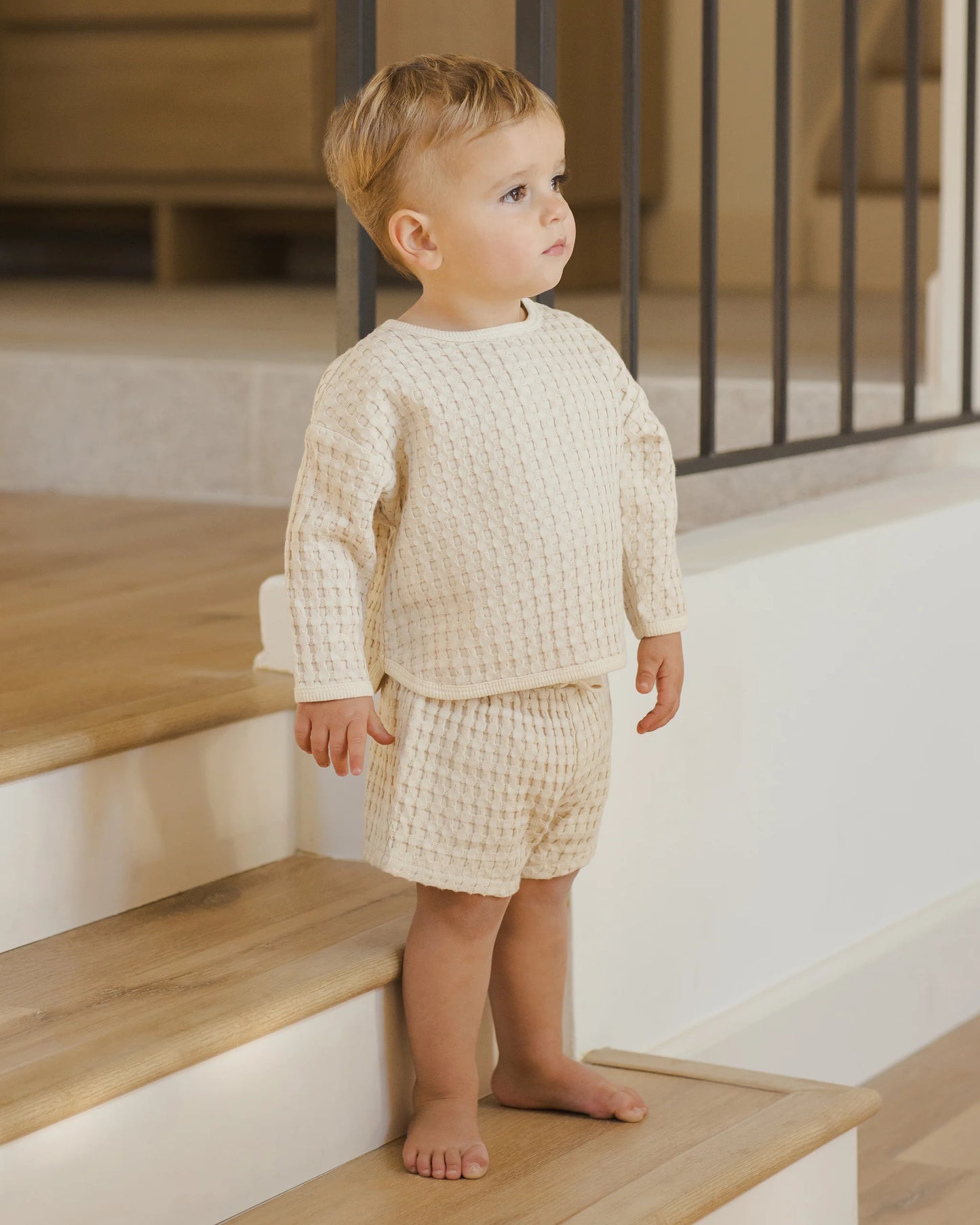 Baby boy wearing Quincy Mae Flynn Set in natural chunky waffle knit, standing to show breathable top and shorts designed for everyday comfort and play.